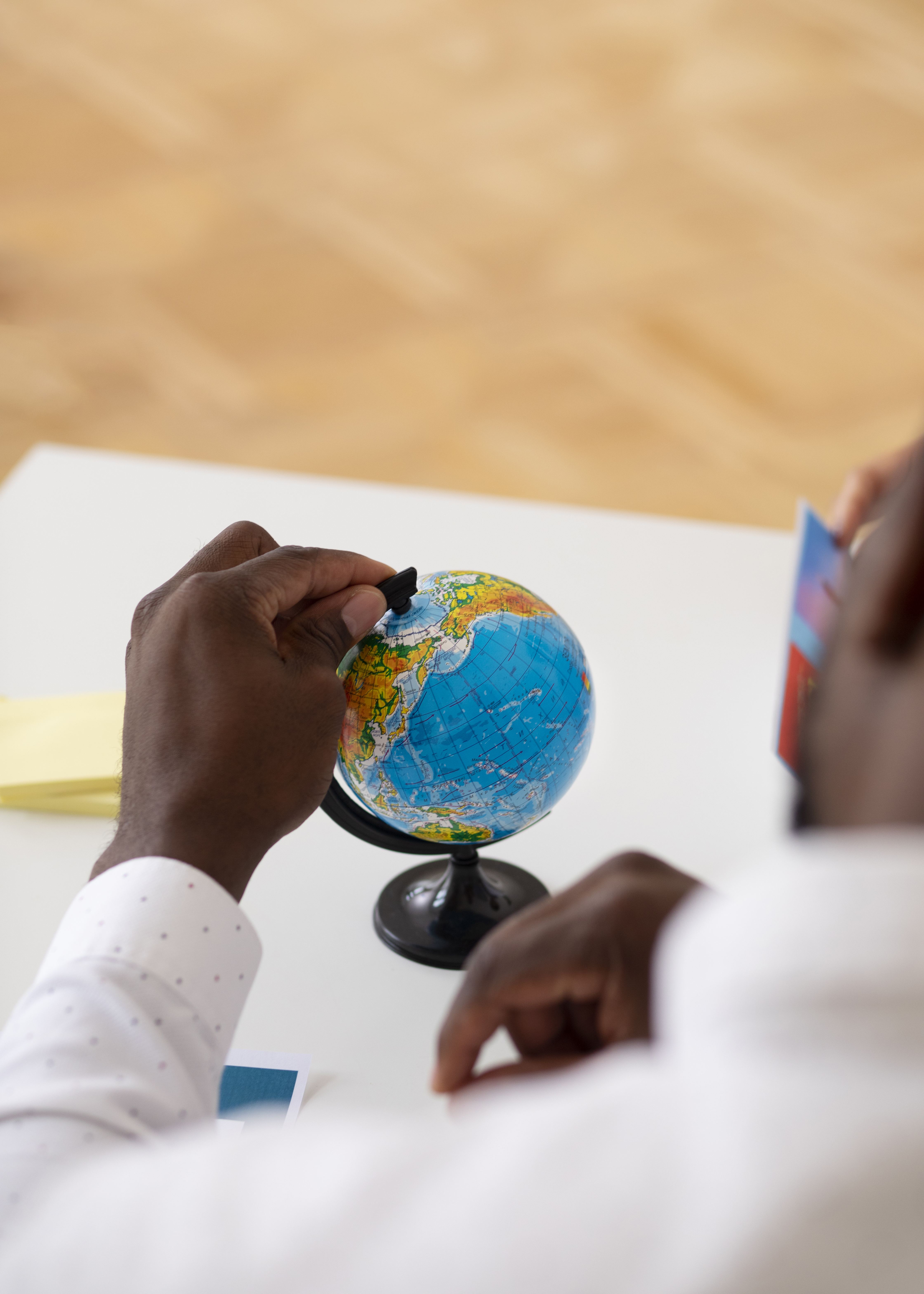 Hands at a desk with a small globe, suggesting cross-border collaboration and global dialogue.